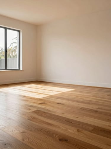 Low-angle architectural shot of a finished living room with warm oak flooring reflecting soft afternoon sunlight, clean minimalist aesthetic.