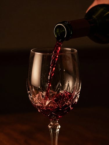Close-up of a hand pouring rich red wine into a crystal glass, low-key directional lighting, warm amber highlights, dark background, shallow depth of field