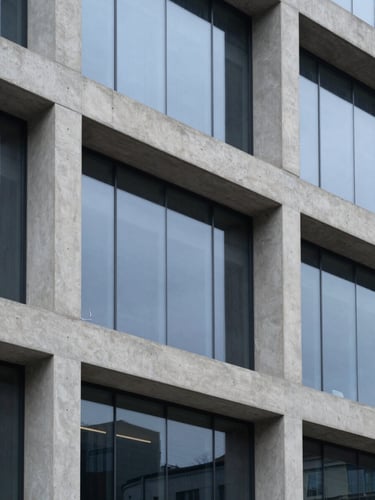Close-up of clean architectural concrete and glass facade, sharp focus, geometric composition, cool overcast daylight, 35mm