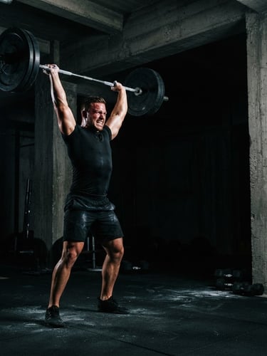 Athlete in a brutalist gym, mid-intense workout, sharp rim lighting highlighting muscular definition, matte black apparel, cinematic 35mm, wide shot bleeding to the right edge.