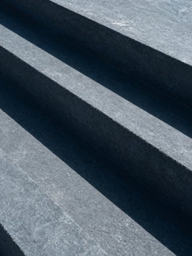 Macro detail of concrete architectural geometric blocks casting sharp diagonal shadows, minimalist composition, slate tones, 35mm