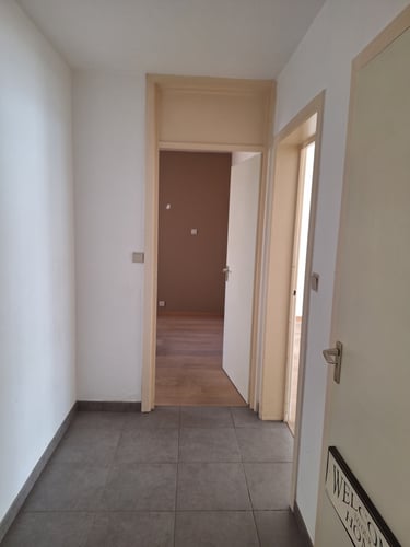 Vue d'un couloir avec des portes beiges avant transformation