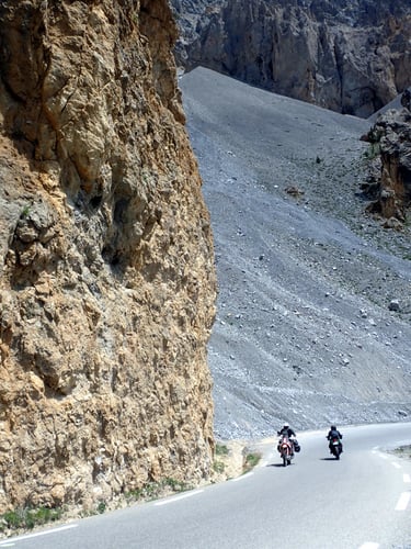 two people riding motorcycles down an alpin mountain side