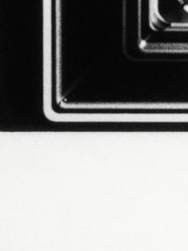 Extreme close-up of photocopied paper texture with harsh high-contrast black and white grain, distorted retro hardware, 35mm film style