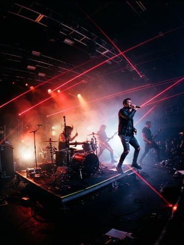 Dynamic low-angle wide shot of a live music concert stage, electric crimson laser beams cutting through deep shadows, hazy atmosphere, high contrast 35mm photography