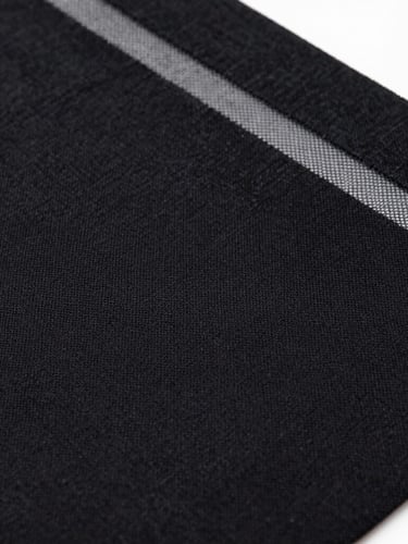 Macro shot of rich black textile ink pressed through a fine silkscreen mesh, high contrast, tactile fabric textures.