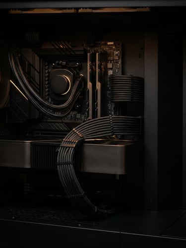 Sharp macro shot of clean, dark cable management inside a high-performance PC case, dramatic rim lighting, amber accents, straight-on architectural angle, moody technical photography.