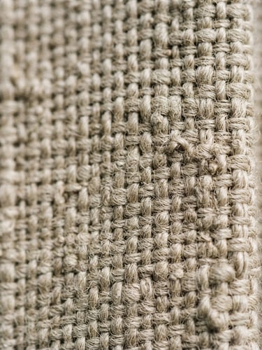 Extreme macro close-up of unbleached heavy linen weave kissing the right edge, soft north-facing morning light, tactile shadows, 35mm film look.