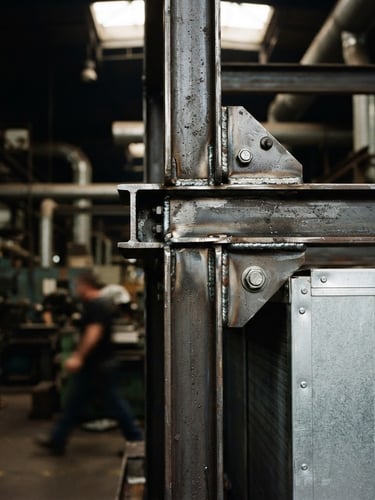Industrial machinery photography, close-up of heavy-duty evaporative condenser steel frame with clean welds, natural factory ambient light, sharp metallic details, 35mm