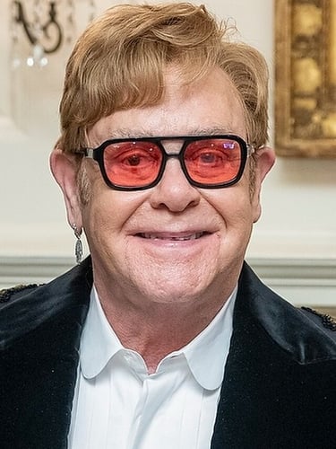 Sir Elthon John in posa con occhiali con lenti rosse
