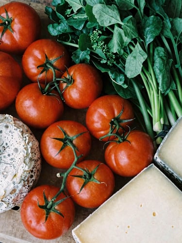 Overhead flat lay of a bustling modern organic food market stall, vibrant heirloom tomatoes and artisanal cheeses, soft natural side-light, Scandinavian editorial style, high-contrast matte finish.