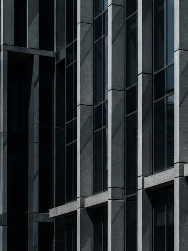 Tight, geometric crop of architectural details of modern corporate concrete and glass facade, high-contrast natural daylight with sharp shadows, deep slate tones.