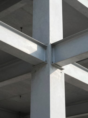 Close-up of exposed structural steel joints and architectural concrete under bright daylight, clean geometric lines, sharp shadows, 35mm lens