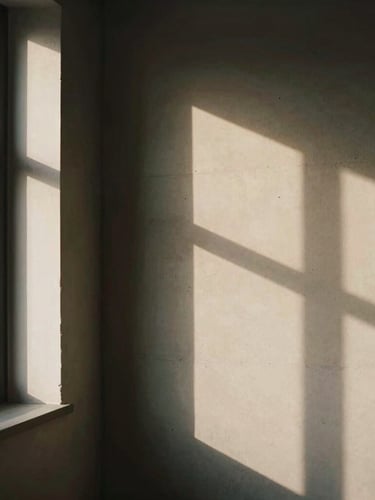 Warm editorial photography of a minimalist design studio interior, soft natural window light casting structured shadows on a concrete wall, deep charcoal and warm mocha tones, 35mm