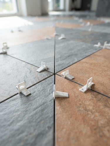 Macro shot of perfectly aligned large-format tiles with leveling clips, bright daylight highlighting the precise grout lines, architectural focus, 35mm