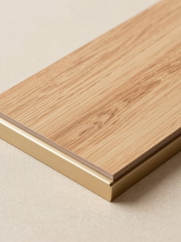 Tactile close-up of premium office materials: light walnut wood sample resting on champagne gold anodized aluminum profile, warm beige fabric background
