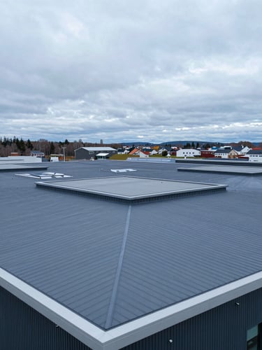 Extreme wide-angle drone shot of a massive modern flat roof with grey PVC membrane, clean geometric lines, overcast Nordic daylight, deep blue and slate tones, 35mm