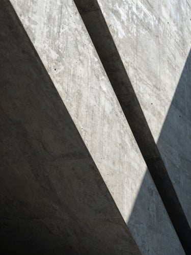 Monolithic concrete architectural detail with sharp, high-contrast geometric shadows under cool diffused light