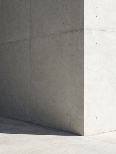 Minimalist architectural concrete corner under harsh sunlight, sharp diagonal shadow, clean geometric lines.