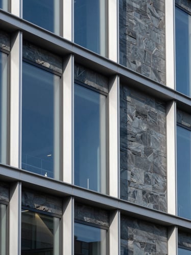Crisp architectural photography of a modern commercial building exterior with clean aluminum frames under bright daylight, slate blue tones.