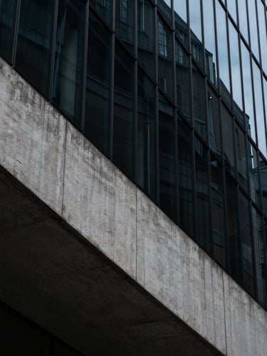 Extreme wide-angle shot of a brutalist concrete and glass facade in London, sharp diagonal shadows, cool ambient light, high contrast
