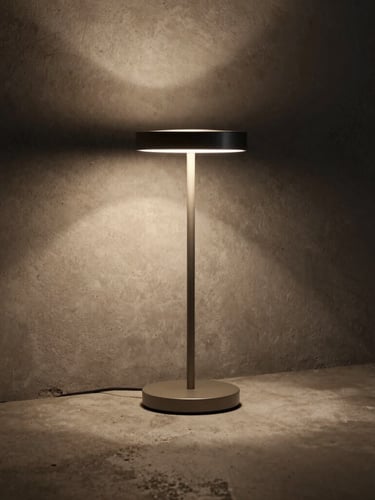 Moody editorial photography of a slim counter table lamp casting a warm pool of light on a raw concrete surface, deep shadows, 50mm