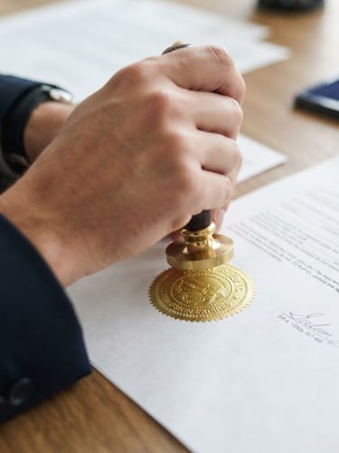 Tight macro shot of a hand holding a gold-embossed notary seal over a clean legal document, bright daylight, 50mm lens.