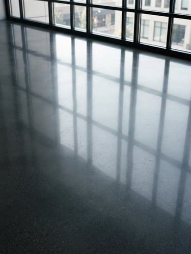 Extreme close-up of a perfectly polished dark gray concrete floor with crisp architectural light reflections, professional commercial interior, 35mm