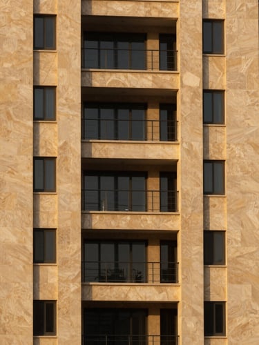 A sharp, high-contrast architectural crop of a high-end residential development in Riyadh, warm golden-hour light reflecting off limestone panels, minimalist landscaping