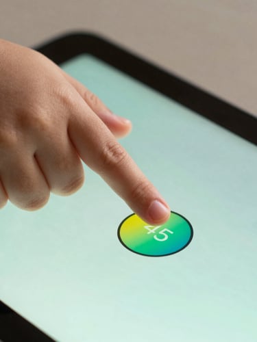 Close-up macro shot of a child's hand tapping a large, vibrant button on an Android tablet, soft mint backlighting, 45-degree angle.