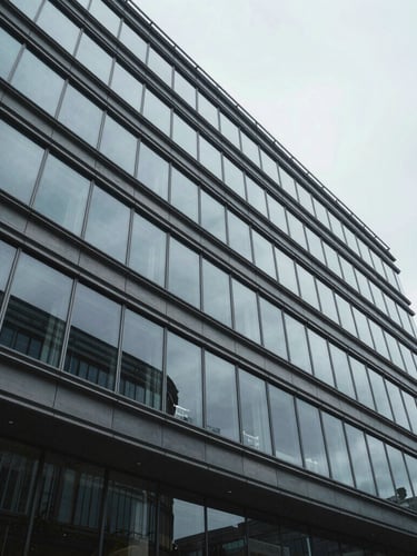 Wide architectural perspective of a modern corporate glass facade, sharp geometric lines, cool overcast daylight.
