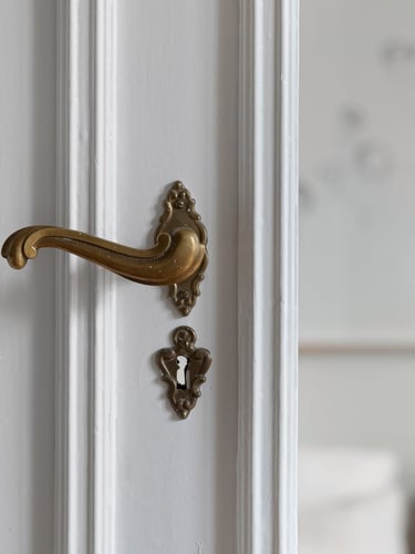 White door with ornate brass door handle and keyhole