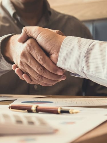 Image of a handshake across a desk between two men