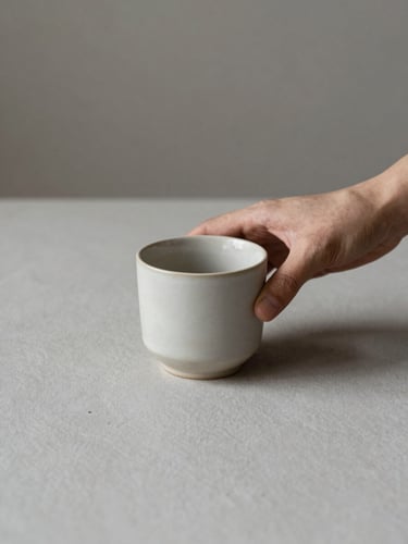 Hands interacting with a tactile ceramic cup on a clean slate surface, soft natural morning light, minimal composition