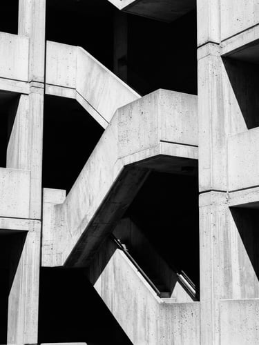 Stark monochromatic architectural crop, sharp concrete angles and deep shadows, high-contrast natural light, editorial 35mm photography