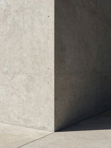 Minimalist architectural corner with sharp shadows and concrete textures, high-contrast natural light, clean editorial framing.