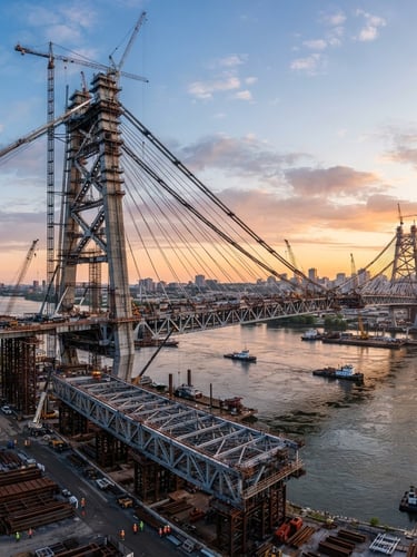 Wide panoramic shot of a massive, modern bridge under construction at sunrise, structural steel girders prominent, sharp daylight, deep slate and steel tones, high contrast, professional corporate.