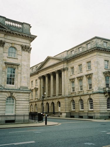 Wide-angle architectural photograph of classic stone financial buildings in Birmingham, soft natural overcast daylight, muted forest green tones, 35mm film grain
