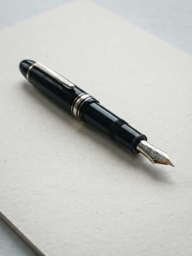 Macro detail of a high-end fountain pen resting on clean, thick cream paper, soft overcast daylight, cool desaturated tones, architectural shadows