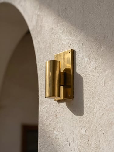 Extreme macro detail of modern Najdi architectural textured plaster meeting a brushed brass fixture, high-contrast interior lighting, deep shadows.