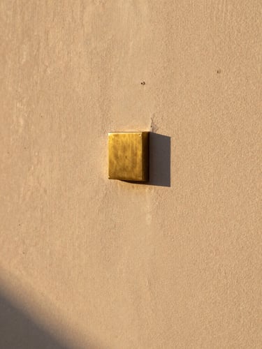Macro detail of modern Najdi textured plaster wall with a brass insert, captured during golden hour with long dramatic shadows
