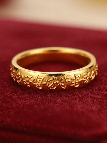Macro photograph of warm, hand-engraved gold jewelry resting on deep crimson velvet, soft side-lighting highlighting the intricate metallic luster, shallow depth of field