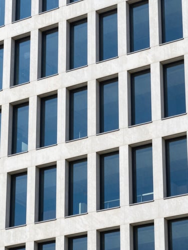 Sharp architectural close-up of modern office building window lines reflecting daylight, clean geometric shadows, 35mm lens
