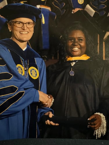 A smiling Spalding University graduate receives her diploma during a formal commencement ceremony.
