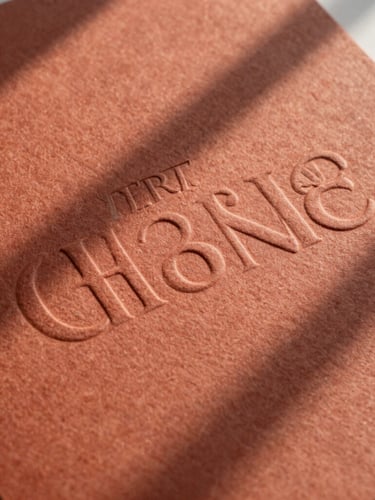 A close-up photograph of heavily embossed premium cardstock with a tactile terracotta texture, soft natural light casting long shadows across the paper substrate.