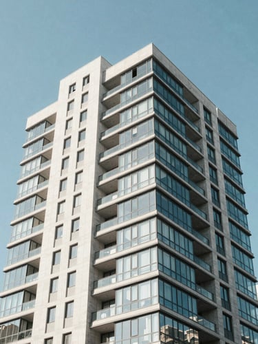 Low-angle architectural photography of a modern residential high-rise with glass and concrete facade in Vitacura, bright crisp morning daylight, clean sharp lines against a clear blue sky, 35mm