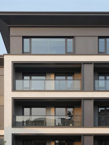 Architectural photography of a modern residential building facade with clean anthracite gray lines and large glass windows under dramatic golden hour light.