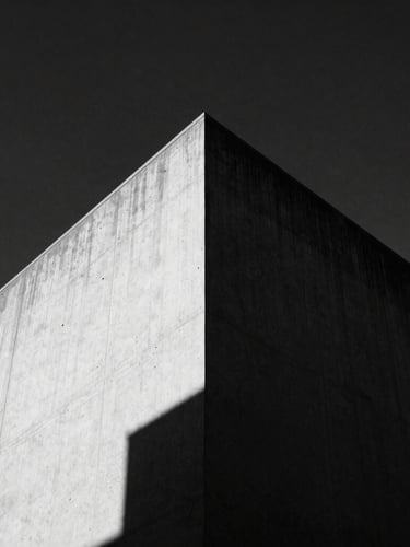 Low-angle high-contrast black and white photograph of a sharp concrete building corner slicing into a dark sky, harsh direct sunlight, deep shadows, 35mm film