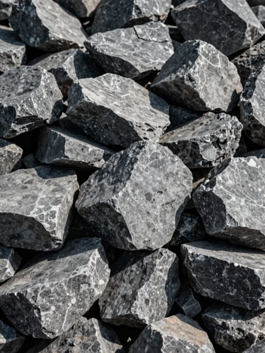 Close-up portrait shot of sharp gray split stone pile at an industrial quarry, hard natural daylight casting deep shadows, raw texture visible