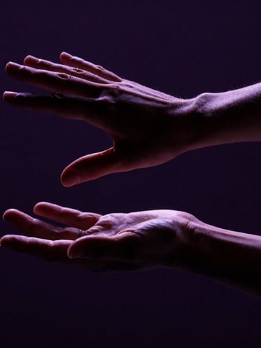 Cinematic editorial photography, dramatic chiaroscuro lighting. An extreme close-up of two dancers' hands in sharp physical tension, fingers sculpted against deep shadows, subtle plum backlighting, 35mm anamorphic lens.